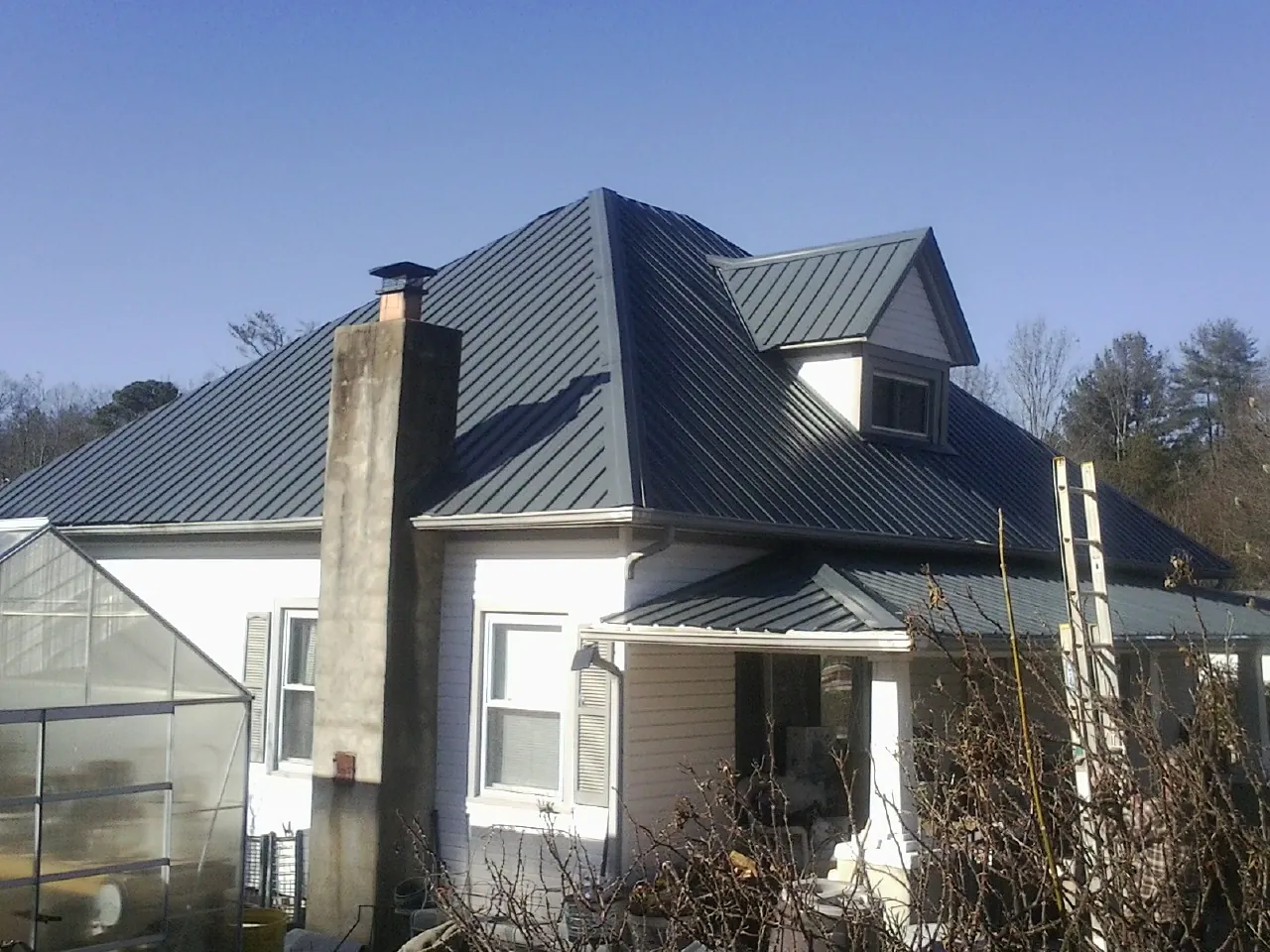 Dark blue standing seam metal roof on a white farmhouse with dormer — Slate & Tile Roof Repair by Roofing Brothers in New Philadelphia