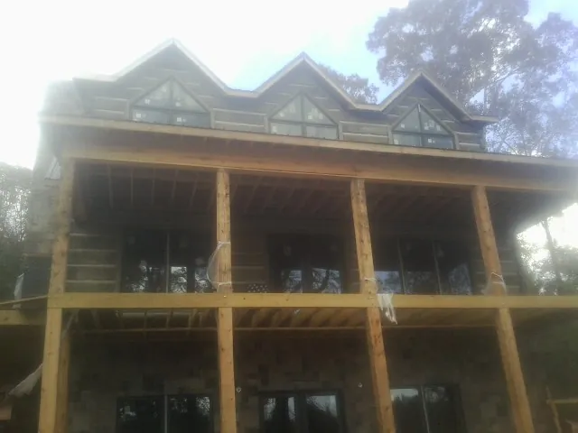 Dormers and porch framing on a large log home under construction — Roof Coating work by our crew in New Philadelphia