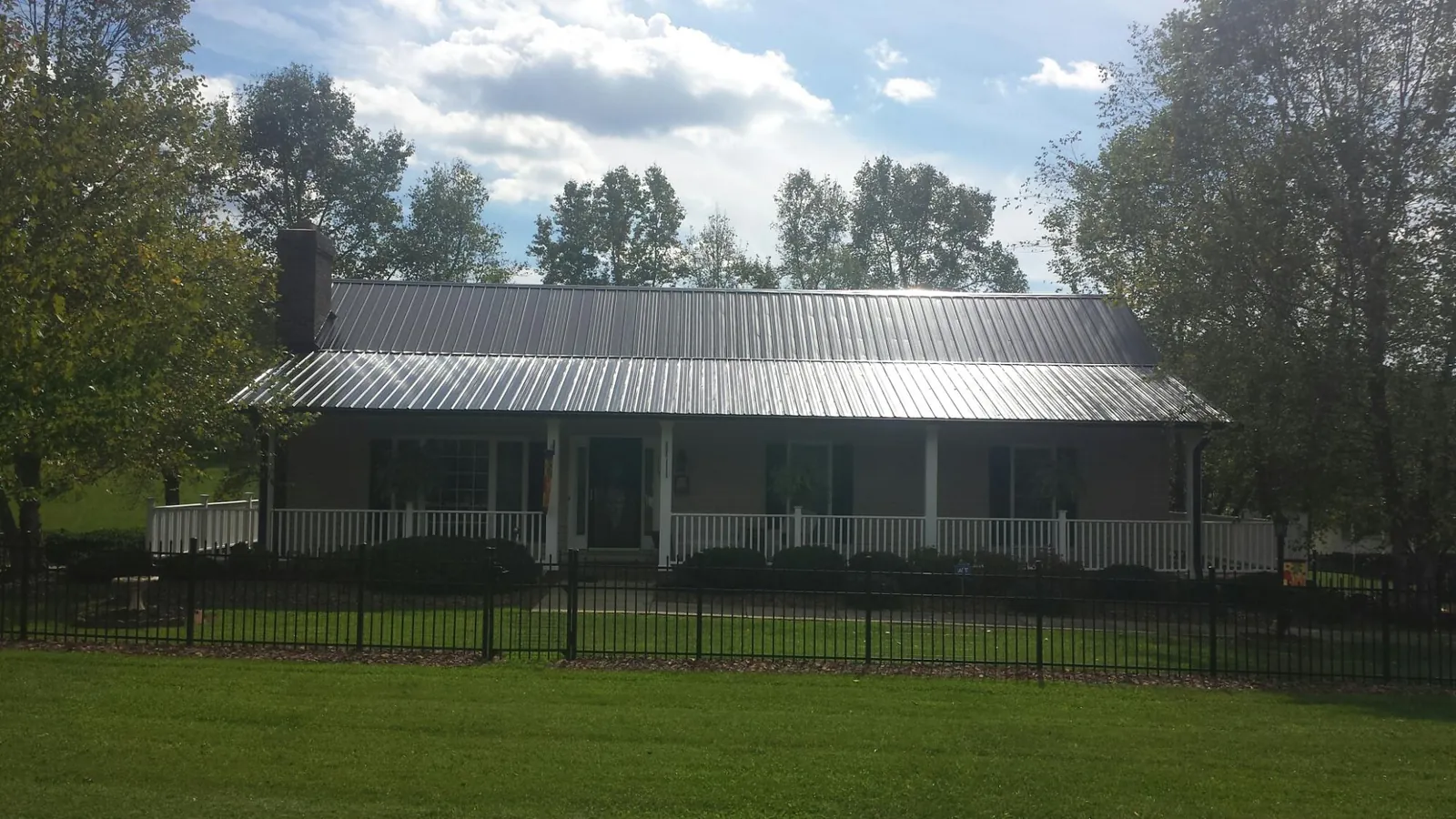 Gray metal roof on a brick ranch with a full width front porch — Gutter Guard Installation work by our crew in New Philadelphia