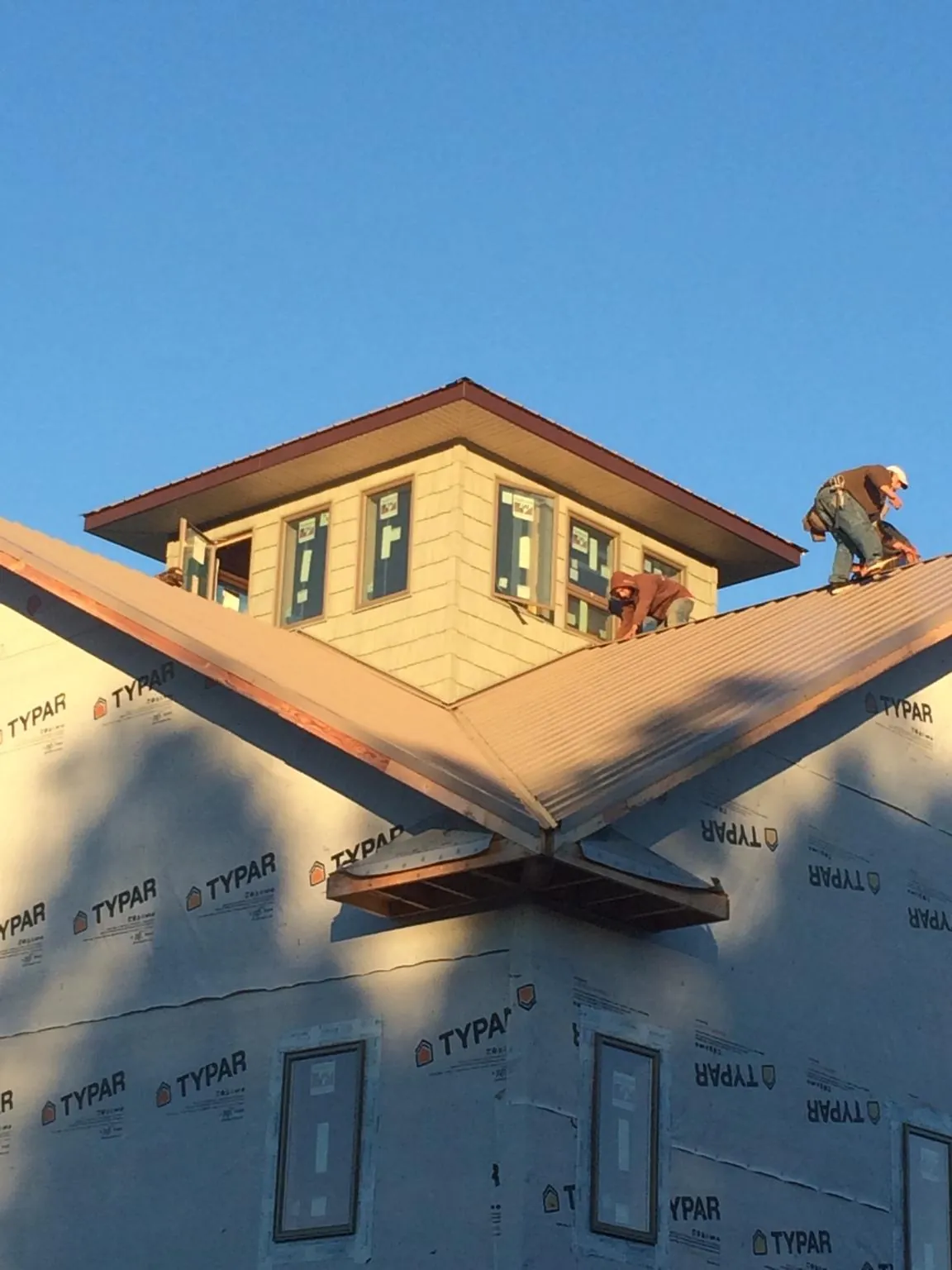 Roofers working around a rooftop cupola on a new metal roof at sunset — Roof Waterproofing in New Philadelphia by Roofing Brothers